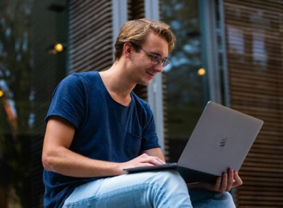 A young man sitting outdoors in Leiden, Netherlands, working on a laptop.